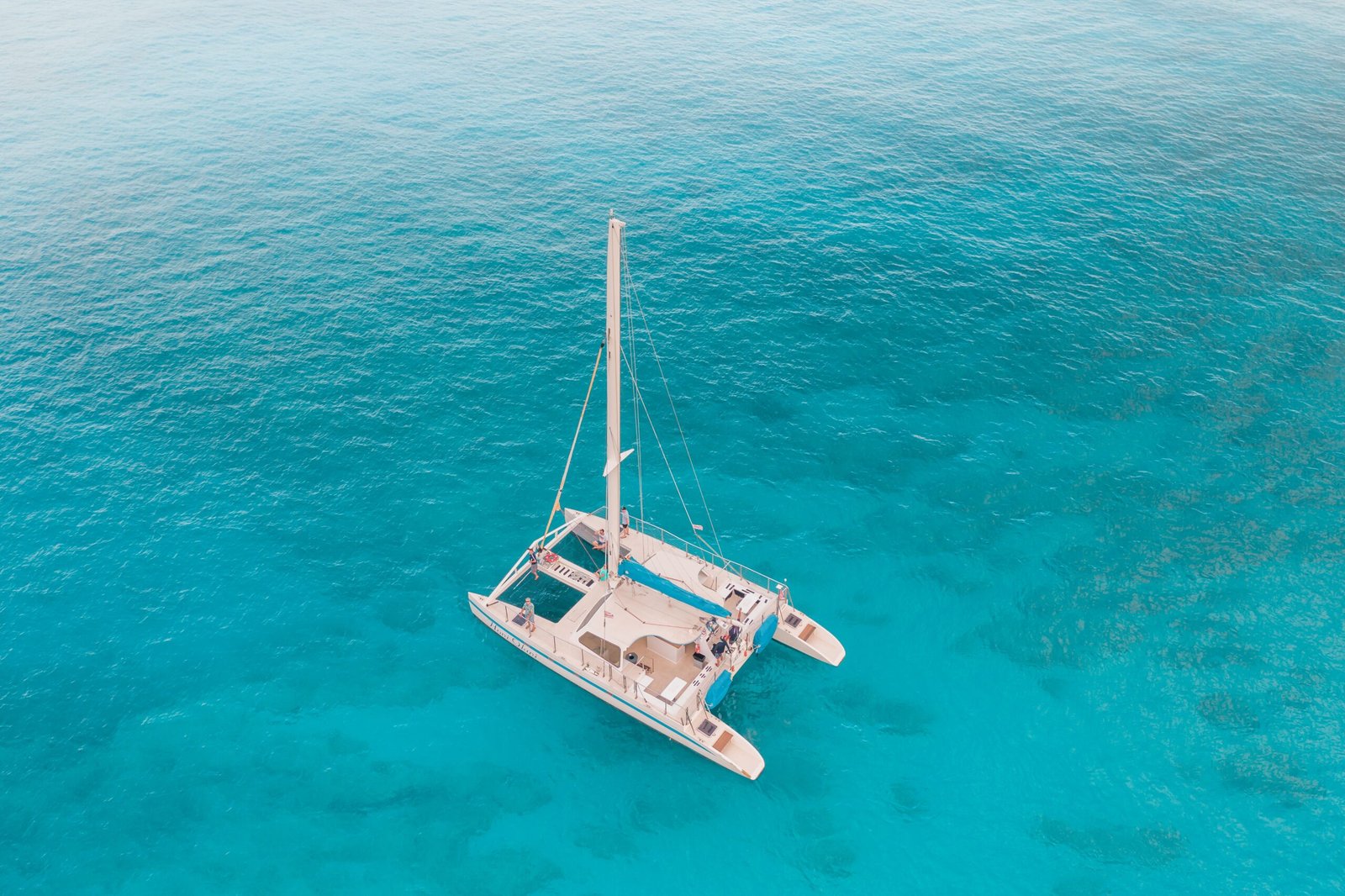 Aerial view of a catamaran sailing in clear turquoise Ionian water