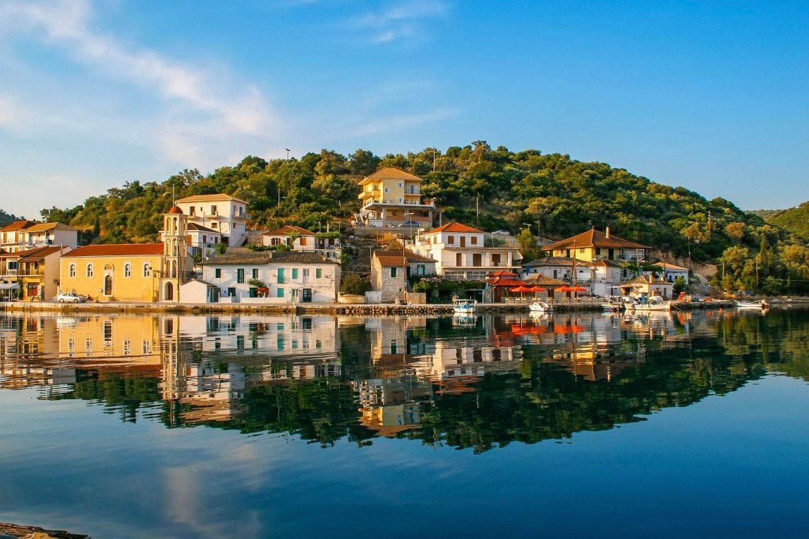 Waterfront houses and boats reflected in the calm water of Vathy Harbour, Meganisi