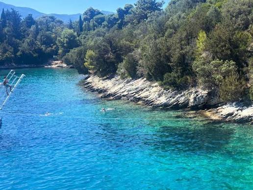Clear turquoise water beside the wooded coastline near Skorpios Island