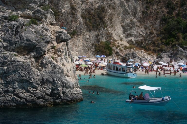 Agiofili’s pebble cove and turquoise water near Vasiliki, with beach visitors and boats